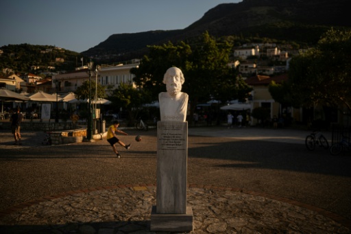 Uma criança joga futebol ao lado de um busto de mármore de Homero em Ítaca — Angelos TZORTZINIS / AFP