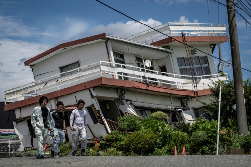 Workers walk past a damaged house and partially collapsed in Yatsushiro, Kumamoto prefecture on July 29, 2026 — Yuichi YAMAZAKI / AFP