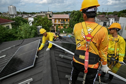Workers install solar panels on a roof in Carmona, in the Philippine province of Cavite — Jam STA ROSA / AFP