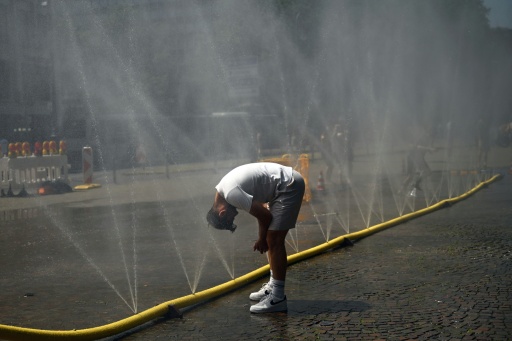 Un hombre se remoja la cabeza con una gran manguera que arroja chorros de agua, instalada en una calle de Colonia para combatir la ola de calor, el 25 de junio de 2026 en esa ciudad al oeste de Alemania — Ina Fassbender / AFP