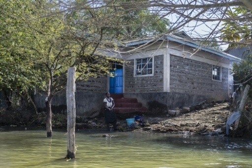 Faith Mpayei, 40 ans, se tient le 28 juillet 2026 à Marigat, au Kenya, devant sa maison, dont l'eau approche du perron après avoir quasiment submergé ce qui était une parcelle de deux hectares — Tony KARUMBA / AFP