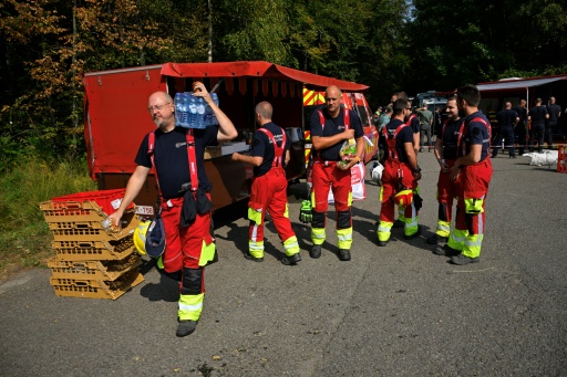 Des pompiers se servent en eau et en nourriture auprès d'un véhicule de soutien logistique des services d'incendie avant de partir lutter contre un feu dans le parc naturel des Hautes Fagnes, le 16 août 2026 à Baelen, dans l'est de la Belgique — JOHN THYS / AFP