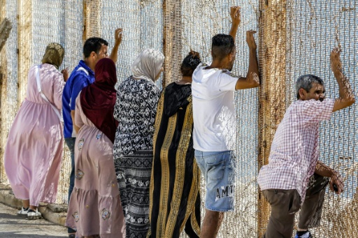 Familiares y amigos esperan junto a una valla de alambre de espino el regreso de las personas que pasaron al enclave español de Ceuta, en el cruce fronterizo de Bab Sebta en Marruecos, en las afueras de Castillejos, el 2 de agosto de 2026 — Abdel Majid BZIOUAT / AFP