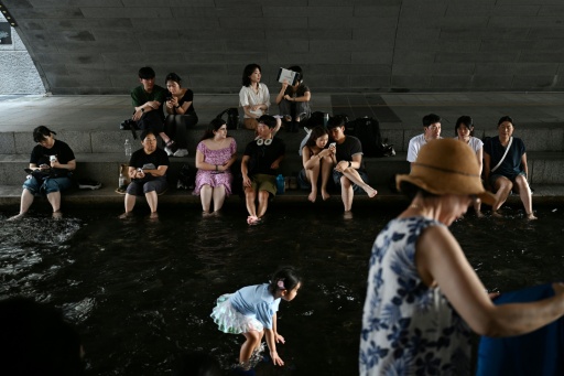 People cool off under a bridge over the Cheonggyecheon Stream in Seoul — GREG BAKER / AFP