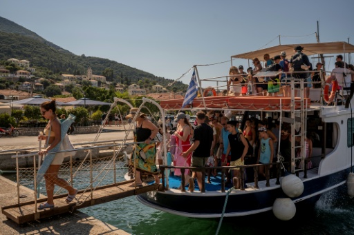 Des touristes débarquent d'un bateau après être revenus des plages voisines de l'île grecque d'Ithaque, dans la mer Ionienne, le 3 août 2026 — Angelos TZORTZINIS / AFP