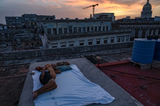 Alexis Miján duerme en una cama improvisada en la azotea de un edificio residencial al atardecer, en La Habana Vieja, el 11 de agosto de 2026. Muchos cubanos duermen en espacios al aire libre durante las noches de verano en busca de alivio frente a las altas temperaturas y los frecuentes apagones. — YAMIL LAGE / AFP