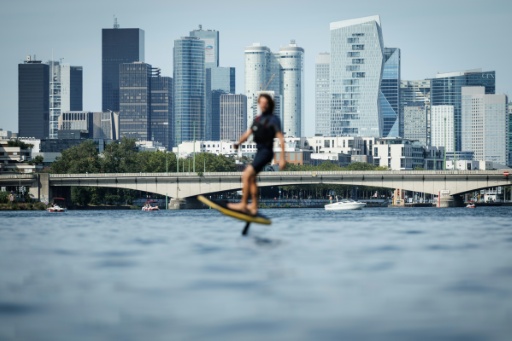 Le moniteur d'e-foil et cofondateur du club Foil in Paris Nicolas Pernodet sur son surf électrique sur la Seine, devant le quartier d'affaires de La Défense, à Paris, le 2 août 2026 — Simon WOHLFAHRT / AFP