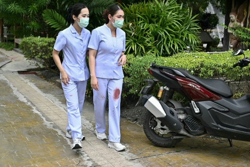 Nurses with blood stains on their scrubs leave the school following the shooting in Bang Kruai district, Nonthaburi province — Lillian SUWANRUMPHA / AFP