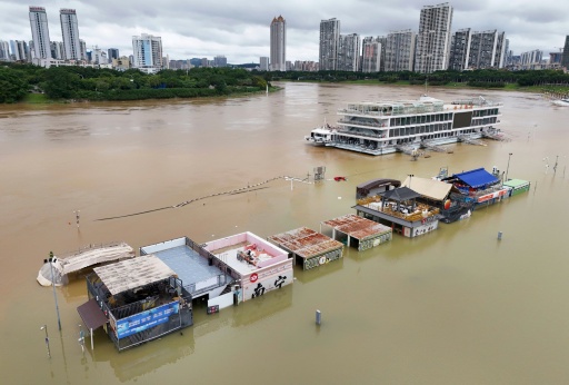 Flooded shops along a submerged riverside walk are seen by the overflowing Yongjiang river in Nanning