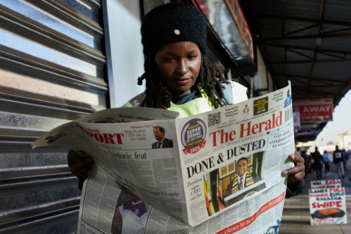 Une femme lit le quotidien d'Etat The Herald à Harare au Zimbabwe, le 8 juillet, au lendemain de la promulgation de la nouvelle constitution par le président Emmerson Mnangagwa. — Jekesai NJIKIZANA / AFP