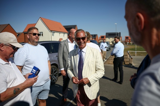 Nigel Farage, (c) chef du parti britannique Reform UK, parle avec des électeurs à la sortie d'un bureau de vote installé dans une école primaire de Walton-on-the-Naze, dans l'Essex, lors de l'élection partielle de Clacton, le 13 août 2026 — Henry NICHOLLS / AFP