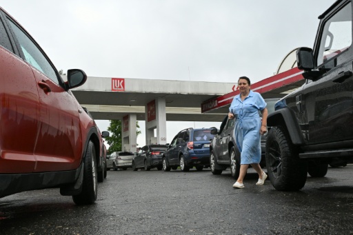 Une femme marche au milieu d'une file de véhicules dans une station-service à Vologda, en Russie, le 14 juillet 2026 — Igor IVANKO / AFP