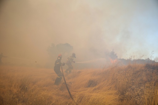 El humo envuelve a unos bomberos que combaten un incendio forestal en la región de Megara, al oeste de Atenas, el 3 de agosto de 2026 — Aris Oikonomou / AFP