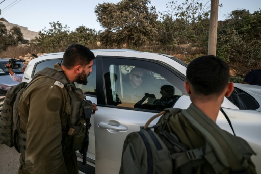 Israeli soldiers watch as US-Palestinian dual citizen Louai Abu Ridi, whose home in the Israeli-occupied West Bank village of Qusra is besieged by Israeli settlers, arrives by car to visit his mother at her home in the same village — JAAFAR ASHTIYEH / AFP