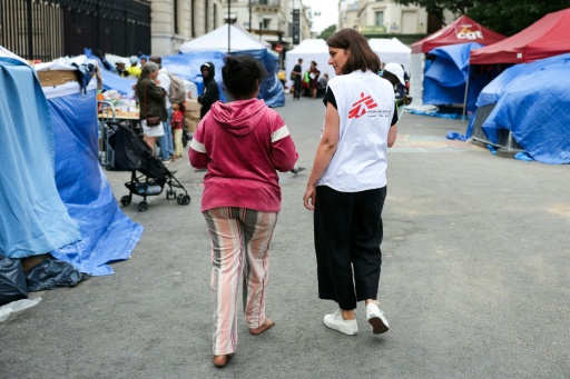 Un membre de Médecins sans frontières parle avec une migrante dans un camp de fortune installé en plein centre de Paris le 21 août 2026 — Thomas SAMSON / AFP