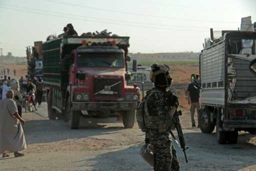 A security officer stands guard as Syrian Kurds head from Hasakeh to Ras al-Ain — Delil SOULEIMAN / AFP