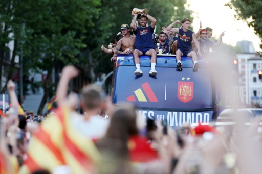 Spain midfielder Rodri holds the World Cup trophy as players parade on a bus through the Madrid streets — Thomas COEX / AFP