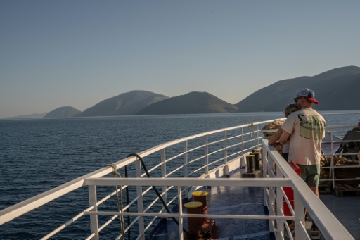 Des touristes sur le pont d'un ferry, le 3 août 2026, en route vers l'île grecque d'Ithaque, patrie d'Ulysse, héros de la mythologie grecque. — Angelos TZORTZINIS / AFP