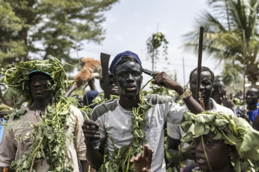 Un chasseur, recouvert de lianes pour éloigner les mauvais esprits, pointe un pistolet sur sa tête lors d'une procession vers le stade de Ngor Siid Ndourà l'occasion de la chasse de Diobaye à Fatick, le 13 juillet 2026. — PATRICK MEINHARDT / AFP