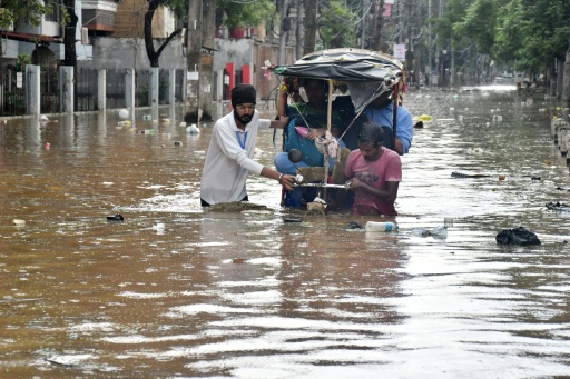 Residents wade through a flooded street following heavy monsoon rains in Guwahati on August 4, 2026 — Biju BORO / AFP