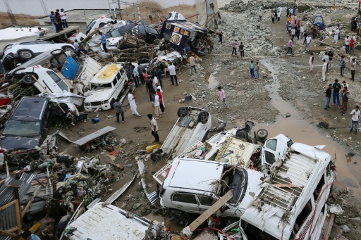 Residents look at damaged vehicles after flash flood and landslide triggered by heavy rains wreaked havoc at Rajouri district in India's Jammu region on July 19, 2026 — Mir Imran / AFP