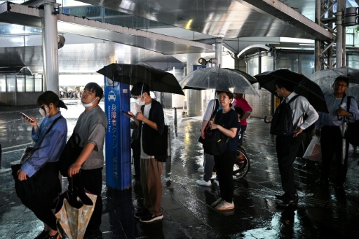 Des personnes attendent un taxi à la station de métro de Chiba, dans la ville de Chiba à l'est de Tokyo, le 13 août 2026, alors que de fortes pluies s'abattaient sur la région — Philip FONG / AFP
