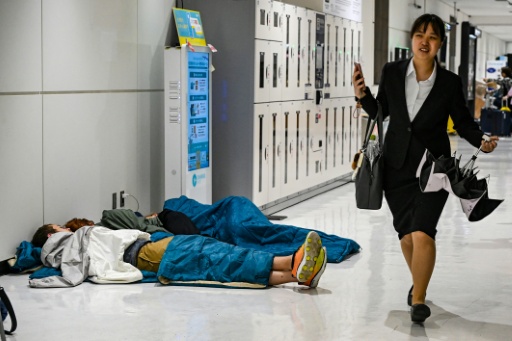 Des passagers dorment à l'aéroport de Narita le 14 août 2026 au Japon — Andrew CABALLERO-REYNOLDS / AFP