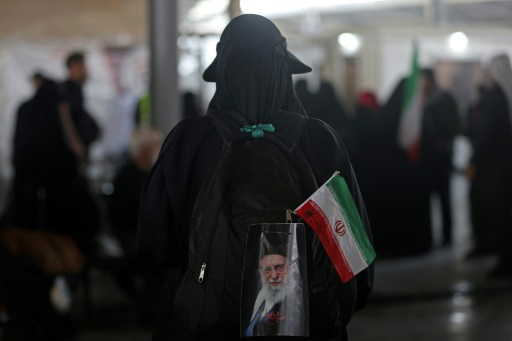 سيدة تحمل حقيبة ظهر عليها علم إيران وصورة للمرشد الأعلى السابق الإيراني علي خامنئي، بعد دخولها من إيران إلى العراق عبر معبر زرباطية في 29 تموز/يوليو 2026 — أحمد الربيعي