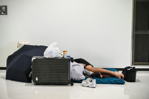 People sleep on the floor of terminal 2 at Narita International Airport after rain delays — Andrew CABALLERO-REYNOLDS / AFP