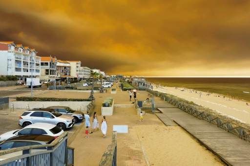 Des vacanciers marchent le long de la plage de Lacanau-Océan, dans le sud-ouest de la France, le 24 juillet 2026, tandis que d'épais nuages de fumée s'élèvent dans le ciel au-dessus d'un incendie de forêt — Maximilien LAMY / AFP