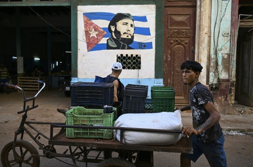 Un joven empuja su triciclo junto a un retrato del fallecido líder cubano Fidel Castro (1926-2016) en La Habana el 10 de agosto de 2026. El 13 de agosto se cumple el centenario del nacimiento del dirigente que condujo la Revolución cubana durante casi medio siglo, mientras muchos de sus seguidores más fieles afrontan una de las peores crisis en décadas, en medio de apagones, escasez e incertidumbre. — YAMIL LAGE / AFP