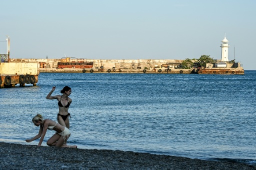 Dos mujeres lanzan piedras al mar, en una playa de Yalta, en la Crimea anexionada, el 21 de julio de 2026 — Igor IVANKO / AFP