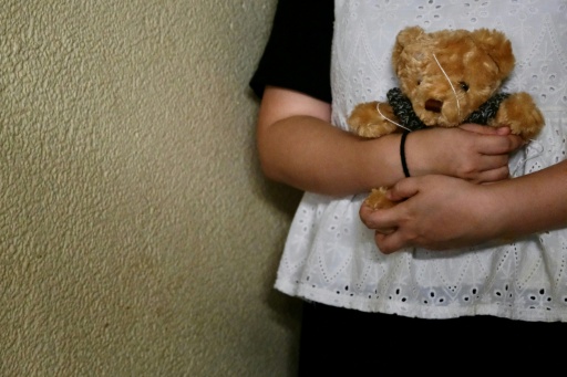 Bobo a woman who suffered persistent child sexual abuse for several years, holds a teddy bear — Tommy WANG / AFP