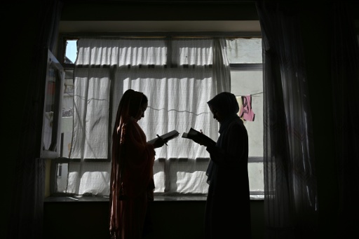 Dos niñas afganas estudiando en casa con su padre — STR / AFP