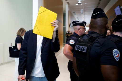 David G., animateur périscolaire, se cache le visage avec un dossier à son arrivée au tribunal où il doit être jugé pour agressions sexuelles sur neuf enfants, le 26 mai 2026 à Paris