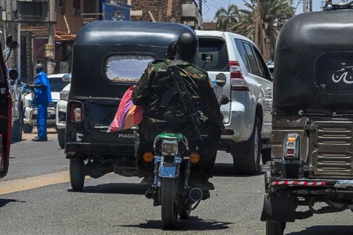 A Sudanese army soldier carries Kalashnikov while riding a motorcycle along the street in Khartoum in April — Khaled DESOUKI / AFP