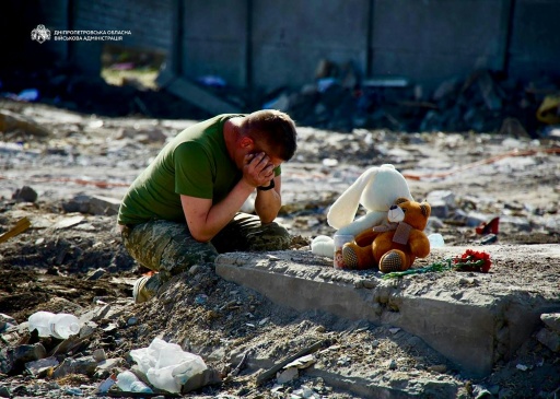 Sur cette photo fournie par l'administration militaire régionale de Dnipropetrovsk le 30 juillet 2026, un homme se recueille après une frappe russe dans le centre de l'Ukraine qui a  laissé dix membres d'une même famille présumés morts — Handout / AFP
