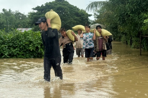Des habitants sur une route inondée après des inondations causées par des pluies de mousson à Kyauktaw, dans l'ouest de la Birmanie, le 10 juillet 2026