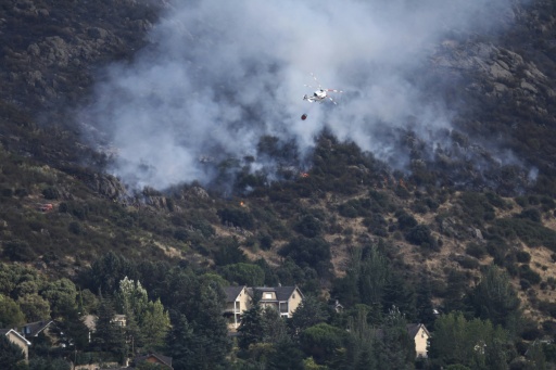 Photo prise le 25 juillet 2026 montrant un hélicoptère versant de l'eau sur un feu qui menace de s'approcher du village de Robledo de Chavela, à 60 km à l'ouest de Madrid — Oscar DEL POZO / AFP