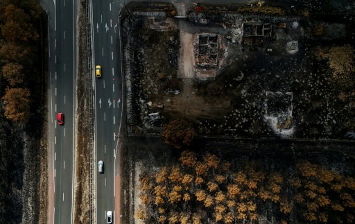 Des voitures circulent sur une route jouxtant des propriétés incendiées, à la suite d'un feu de forêt qui a fait rage en Gironde, à Lanton, le 4 août 2026 — Christophe ARCHAMBAULT / AFP
