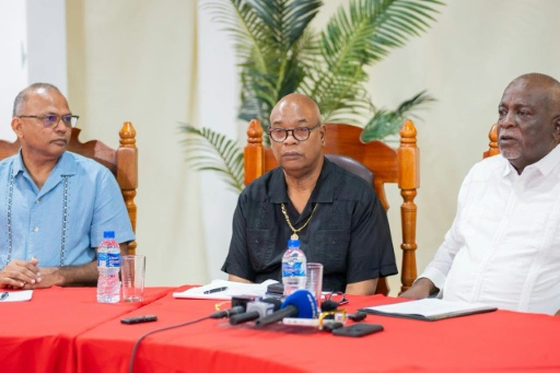 Photo diffusée par NCN Guyana montrant (g-d) le ministre de la Santé du Guyana, le Dr Frank Anthony, le ministre des Travaux publics du Guyana, Juan Edhill, et le Premier ministre du Guyana, Mark Phillips, lors d'une conférence de presse à Georgetown, le 19 juillet 2026, après le chavirage d'un ferry au Guyana — Handout / AFP