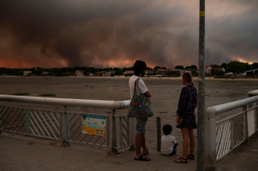 Des gens regardent les fumées d'un incendie à Lège-Cap-Ferret depuis la plage d'Andernos-les-Bains, en Gironde, le 23 juillet 2026 — Olivier MORIN / AFP