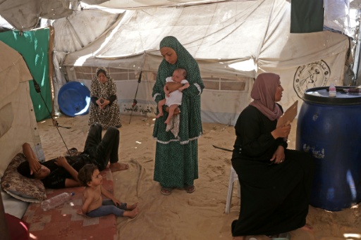 Rouba, petite Palestinienne (à gauche) souffrant de la varicelle, avec des membres de sa famille sous la tente où ils habitent dans le camp de Khan Younes, à Gaza, le 19 juillet 2026 — Bashar Taleb / AFP
