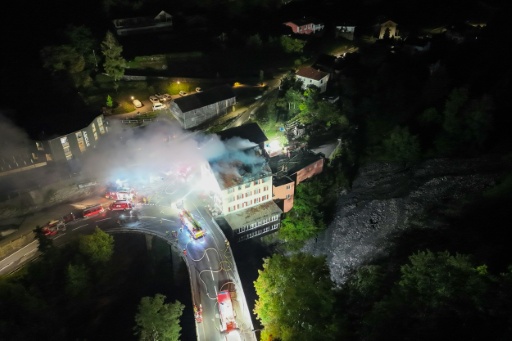 Vue aérienne, prise et diffusée le 21 août 2026 par la police cantonale des Grisons (Kantonspolizei Graubünden), montrant des pompiers éteignant un incendie qui s'est déclaré dans un bâtiment à Thusis, dans l'est de la Suisse — Handout / AFP