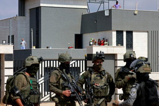 Des soldats israéliens devant l'entrée d'une maison palestinienne assiégée par des colons israéliens dans le village de Qusra, au sud de Naplouse, en Cisjordanie occupée, le 14 août 2026 — Jaafar ASHTIYEH / AFP