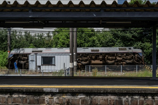 Un homme parle au téléphone à côté d’un train qui a déraillé et s’est renversé à Yatsushiro, dans la préfecture de Kumamoto, le 29 juillet 2026, après qu’un tremblement de terre a frappé le sud-ouest du Japon la veille — Yuichi YAMAZAKI / AFP