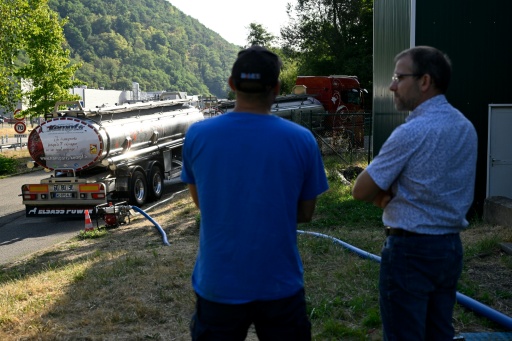 Xavier Barbin, directeur adjoint du Syndicat des eaux et de l'assainissement (SDEA) Centre-Alsace, à droite, discute avec employé du SDEA pendant qu'un camion-citerne ravitaille en eau la commune de Sainte-Marie-aux-Mines, dans le Haut-Rhin, le 11 août 2026 — Jean-Christophe VERHAEGEN / AFP