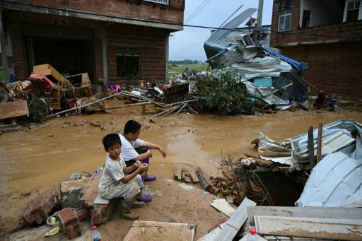 Des enfants sont assis près de maisons endommagées après l'effondrement, le 6 juillet, du réservoir de Liulan, dans le village de Liulan, à Hengzhou, dans la région chinoise du Guangxi (sud-ouest), le 8 juillet 2026.