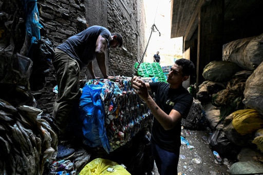 Egyptian families live and work in spaces barely separated from mountains of waste — Khaled DESOUKI / AFP