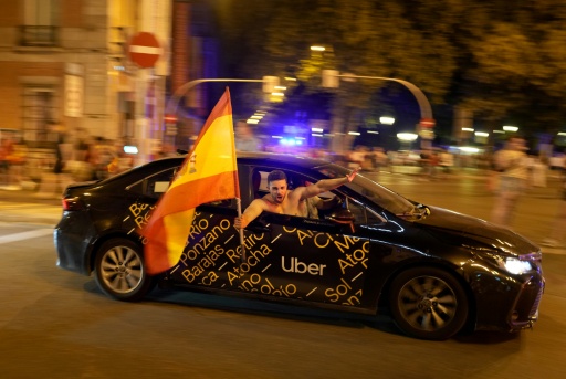 Un supporter agite un drapeau de l'Espagne dans un taxi à Madrid le 19 juillet 2026 après la vicoire de la Roja en finale de la Coupe du monde — Paul Hanna / AFP